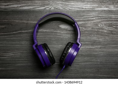 Stylish headphones on wooden background, top view