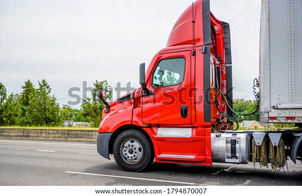 Stylish\
Heavy loaded classic red big rig semi truck with roof spoiler\
transporting commercial cargo at dry van semi trailer running on\
the straight wide divided multiline highway\
road