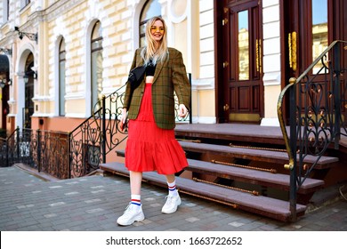 Stylish Hipster Woman Posing On The Street Wearing Trendy Modern Fashion Casual Outfit, Jacket Crop Top, Skirt And Sneakers, Blogger Style, Old European Architecture Around, Spring Autumn Season.