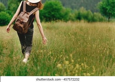 stylish hipster woman walking in grass and holding  in hand herb  wildflowers  in summer mountains, travel concept, peaceful relaxing moment. happy earth day - Powered by Shutterstock