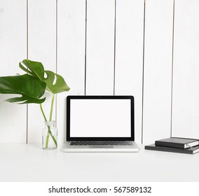 Stylish Hipster Workspace With Laptop Computer, Black Notebooks, Monstera Leaves In Vase At Home Or Studio.Desktop Computer Screen Isolated. White Desk Mockup