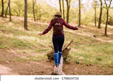 Stylish Hipster Young Woman Walking In The Forest, Carrying A Backpack In The Forest On Sunset Light In The Spring Season, Looking At Amazing Woods, Travel Concept, Space For Text