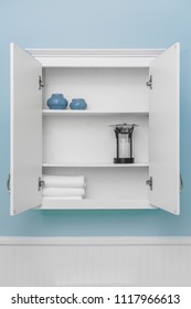 Stylish Home Decor On Shelves Of Clean White Cabinet, Empty Space For Product Display, Light Blue Wall Paint, White Beadboard Or Wainscoting