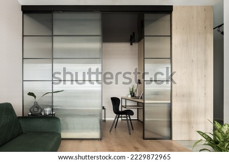 Stylish home office space in living room with tempered glass wall and sliding doors