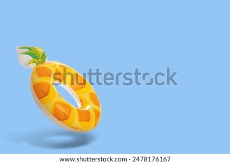 Stylish inflatable pineapple shaped ring in air on light blue background. Space for text