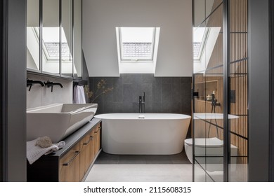 Stylish interior of bathroom with bathtub, shower, towels and other personal bathroom accessories. Modern and design interior concept. Roof window. Template.