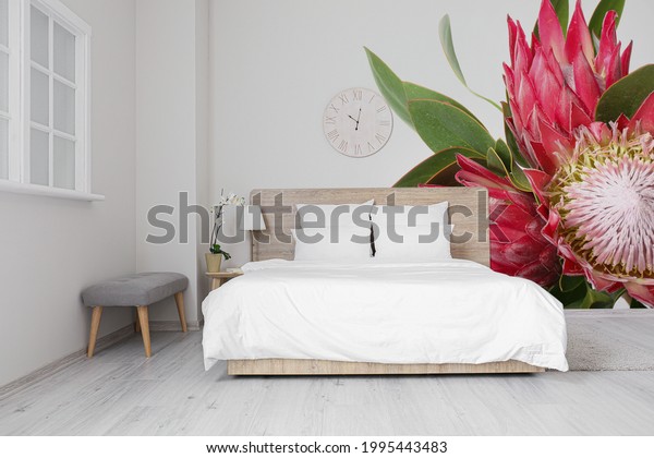 Stylish interior of bedroom with beautiful exotic flowers painting on wall.