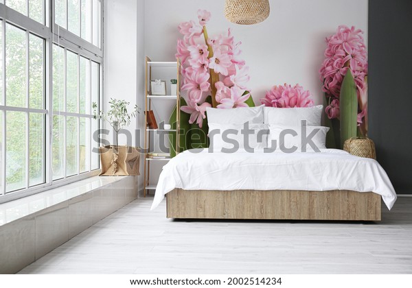 Stylish interior of bedroom with beautiful hyacinth flowers on wall