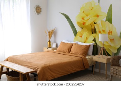 Stylish interior of bedroom with beautiful narcissus flowers on wall
