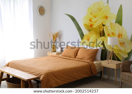 Stylish interior of bedroom with beautiful narcissus flowers on wall