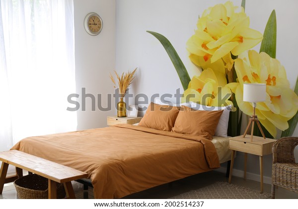 Stylish interior of bedroom with beautiful narcissus flowers wallpaper on wall.