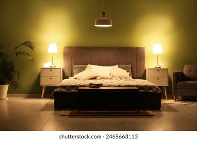 Stylish interior of bedroom with glowing lamps late in evening