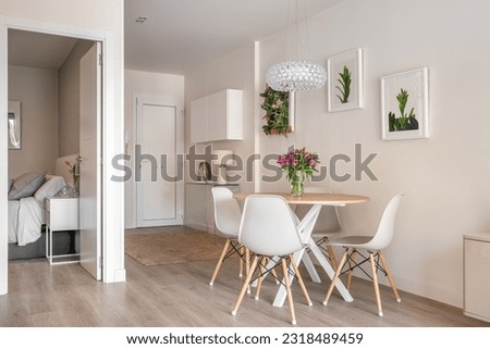 Stylish interior in a compact apartment with a spacious combined living room with table, chairs and decorative accessories overlooking the open bedroom. Cozy city apartment