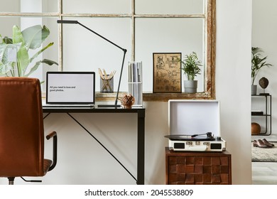 Stylish interior design composition of modern masculine home office workspace with black industrial desk, brown leather armchair, laptop, vintage player and stylish personal accessories. Template. - Shutterstock ID 2045538809