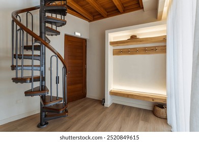 
Stylish interior design detail featuring entrance hall with modern, open-plan wardrobe that showcases organized storage and elegant decor. Focal point of space is striking spiral metal staircase - Powered by Shutterstock