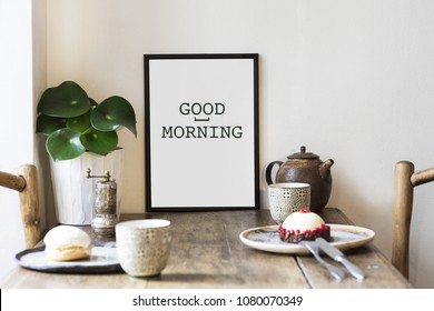 Stylish Interior Design Of Kitchen Space With Small Table With Mock Up Frame, Plant, Cups Of Tea And Tasty Dessert.