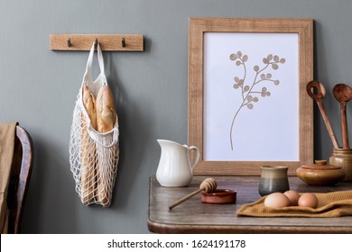  Stylish interior design of kitchen space with mock up photo frame, wooden table, cup of tea, eggs, bagles and kitchen accessories. Cozy home decor of kitchen space. Template. 
