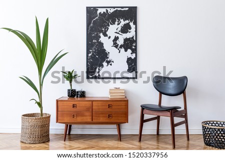 Stylish interior design of living room with wooden retro commode, chair, tropical plant in rattan pot, basket and elegant personal accessories. Mock up poster frame on the wall. Template. Home decor.