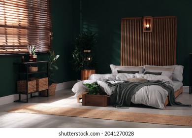 Stylish interior with large comfortable bed and potted plants