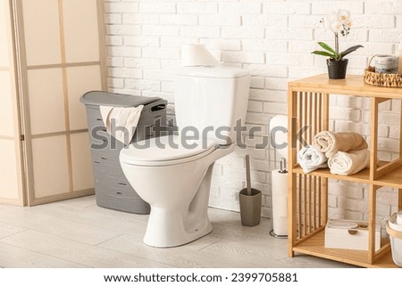 Stylish interior of light restroom with laundry basket