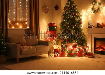 Stylish interior of living room with beautiful Christmas tree and fireplace at night