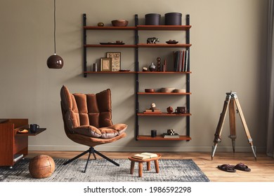 Stylish Interior Of Living Room With Design Brown Armchair, Wooden Bookcase, Pendant Lamp, Carpet Decor, Picture Frames And Elegant Personal Accessories In Modern Retro Home Decor. Template.