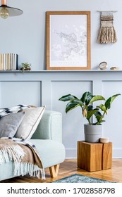 Stylish interior of living room with mock up poster frame, design sofa, wooden cube, pendant lamp, plant, carpet, pillows, plaid, books, clock and elegant personal accessories in modern home decor. - Shutterstock ID 1702858798