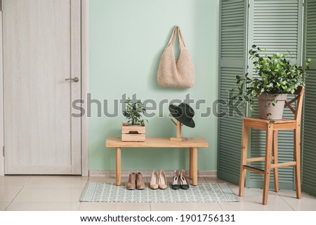 Stylish interior of modern hall with table, houseplants and shoes