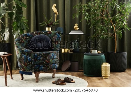 Stylish interior of modern living room with retro design armchair, plants, pouf and creative perosnal accessories. Urban jungle concept. Template.