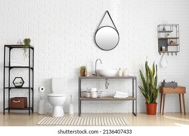 Stylish interior of restroom with toilet bowl, modern sink and holder with toilet paper rolls - Shutterstock ID 2136407433
