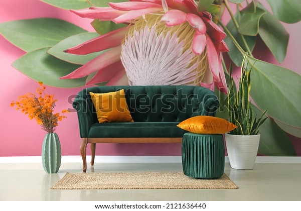 Stylish interior of room with sofa and beautiful protea green floral wallpaper deign on wall.
