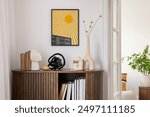 Stylish interior with a wooden cabinet plants, decorative objects, and books. A vibrant mock up art piece featuring a sunburst design adds a pop of color. Minimalist home decor. Template.