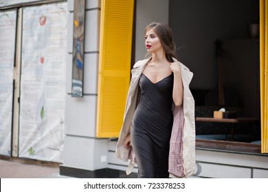 Stylish Joyful Fashionable Girl With Style Hairstyle, Stylish Coat And Modern Black Dress Walking On The Street In City Center. Fashion Look, Happiness.