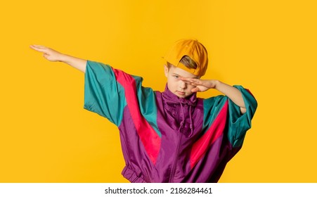 Stylish Kid Boy In 80s Sport Suit And Cap On Yellow Background