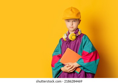 Stylish Kid Boy In 80s Sport Suit And Cap With Notebooks On Yellow Background