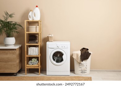 Stylish laundry room interior with washing machine, furniture and houseplant