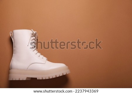 Stylish leather shoe on light brown background, top view. Space for text