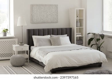 Stylish light bedroom interior with large comfortable bed, shelving unit and bedside table