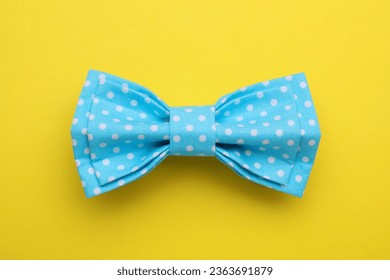 Stylish light blue bow tie with polka dot pattern on yellow background, top view - Powered by Shutterstock