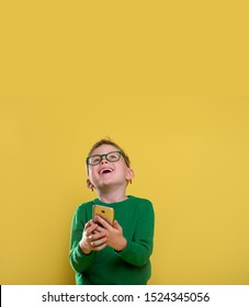 Stylish Little Boy Looking Up And Holding Mobile Phone. Happy Child Using Mobile Phone. Addicted Kid Of Social Networks. Child Playing On Phone.