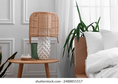 Stylish living room interior with bed, bedside table, lamp and houseplants