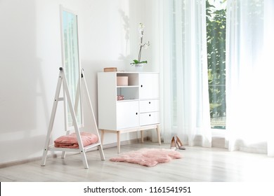 Stylish Living Room Interior With Chest Of Drawers And Mirror