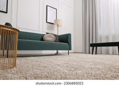 Stylish living room with soft beige carpet, coffee table and sofa, low angle view. Interior design