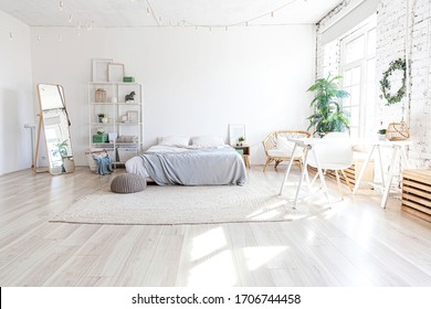 Stylish loft bedroom interior. Spacious design apartment with light walls large windows big bed. Clean modern decoration with elegant furniture in minimalist Scandinavian style
