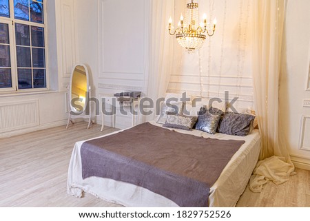 Stylish loft bedroom interior. Spacious design apartment in baroque style with light walls elegant furniture king size big bed. Beautiful luxury classic white bright clean interior bedroom