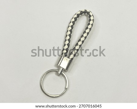 A stylish loop keychain featuring a blackwhite braid and a gold-toned metal fitting and keyring. The background is simple white for contrast.