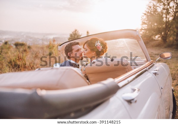 Stylish Loving wedding couple kissing and hugging on\
nature near retro car