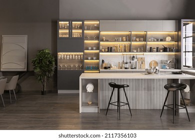 stylish luxury kitchen interior in an ultra-modern spacious apartment in dark colors with super cool led lighting and an island for cooking and a dining table area - Shutterstock ID 2117356103