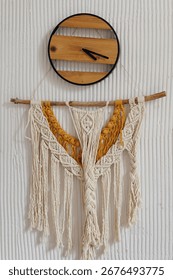 Stylish macrame and weaving wall decor hanging underneath a wooden clock