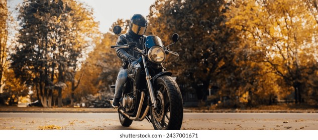 stylish male motorcyclist in a leather jacket and jeans with a classic city motorcycle